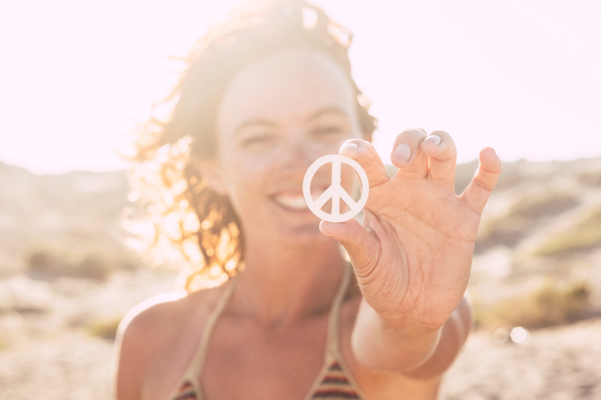 beautiful woman showing the symbol of the peace at the beach alone